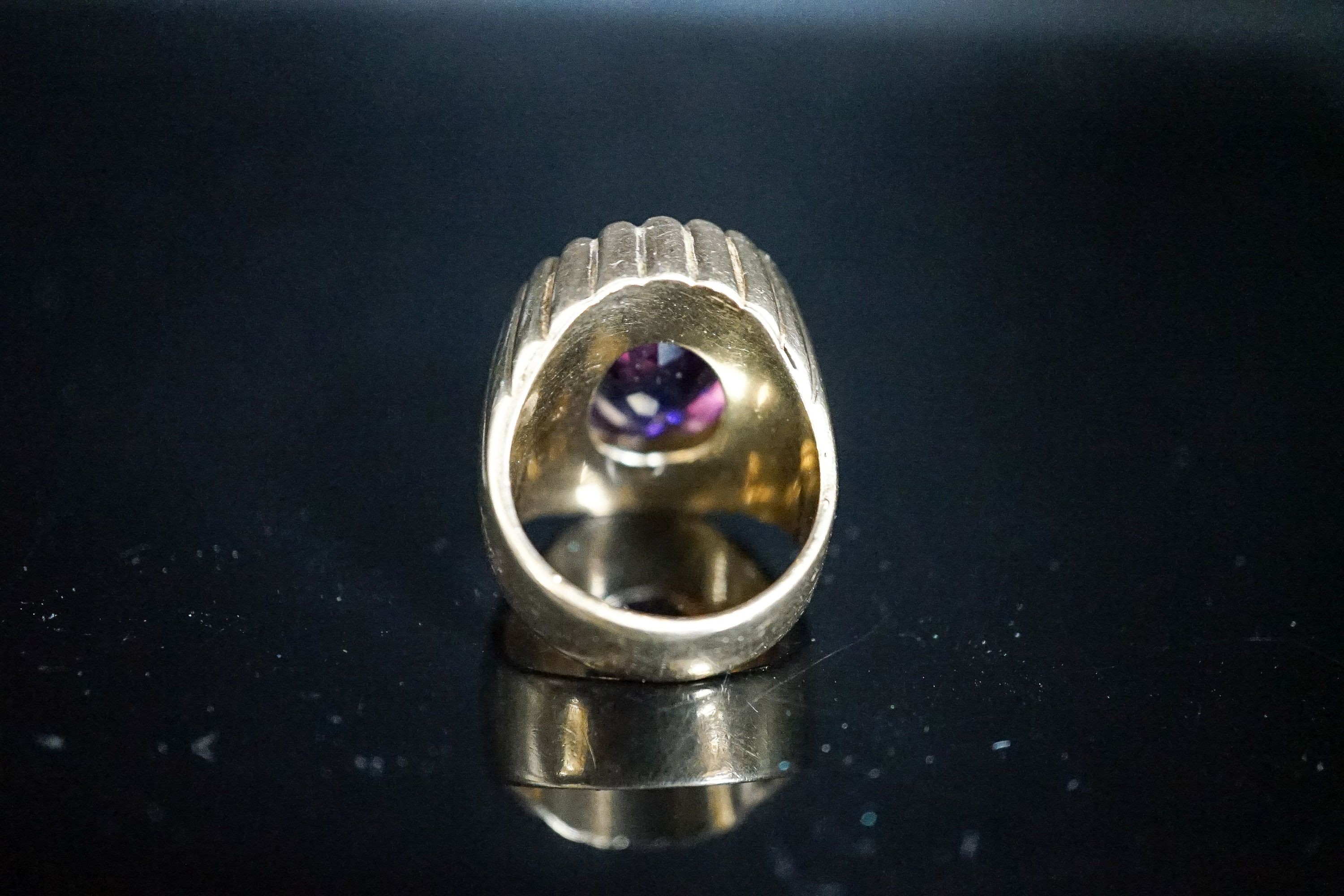 A yellow metal and oval cut amethyst set dress ring, with fluted setting, size Q/R, gross 17 grams.